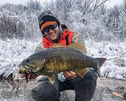 Angler holding a large bass in snowy winter conditions