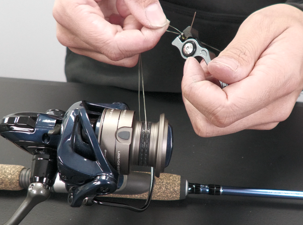 angler tying fishing line to a spinning reel