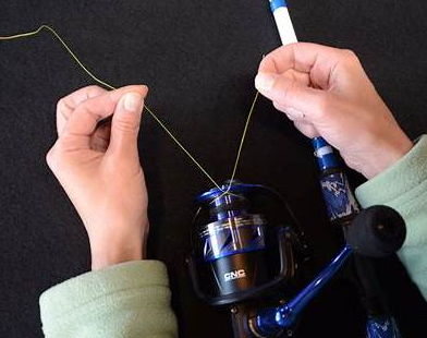 hands spooling fishing line onto a reel