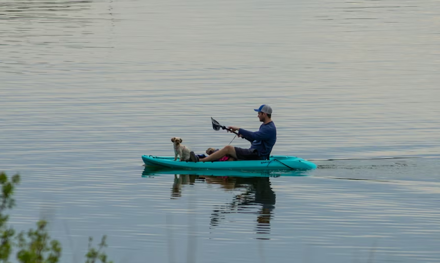 Angler fishing from a kayak on a calm lake near likely structure